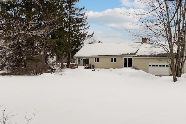 snow covered rear of property featuring a garage