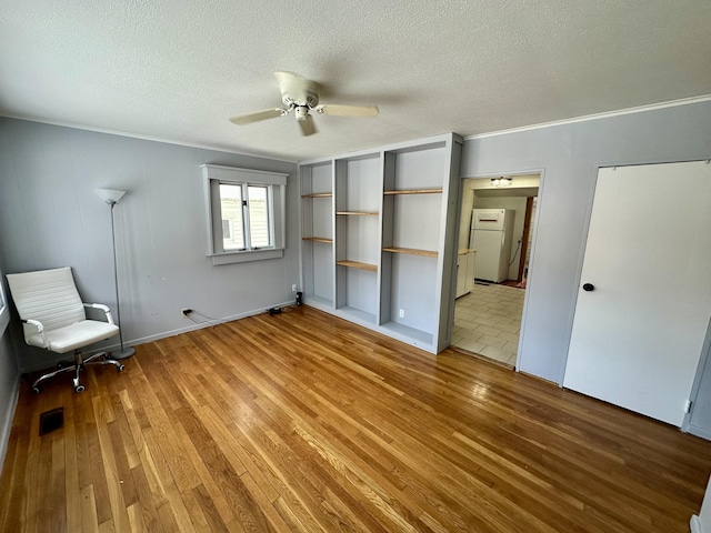 unfurnished bedroom with a textured ceiling, ceiling fan, visible vents, freestanding refrigerator, and light wood finished floors