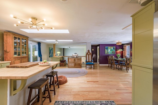 dining area with a notable chandelier, light wood-style flooring, and a skylight