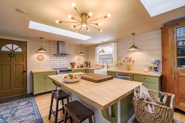 kitchen featuring butcher block countertops, a skylight, wall chimney exhaust hood, and green cabinetry