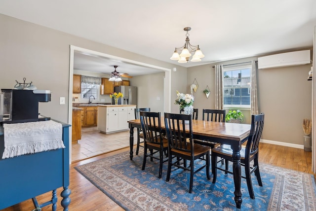 dining room featuring plenty of natural light, light wood-style flooring, ceiling fan with notable chandelier, and a wall mounted air conditioner