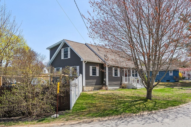 view of front of home featuring fence, a shingled roof, and a front yard