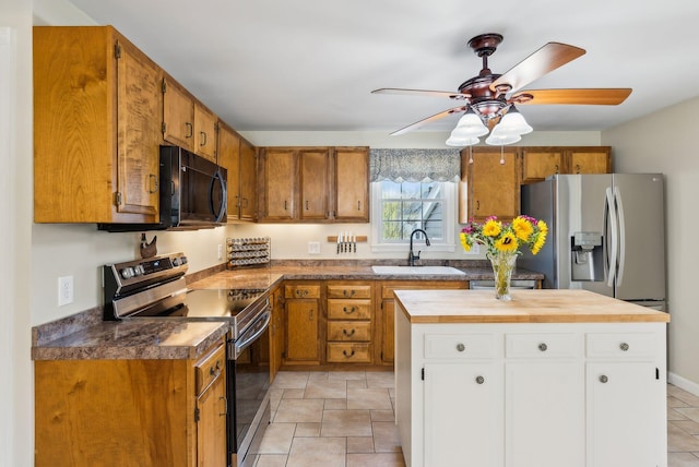 kitchen featuring ceiling fan, appliances with stainless steel finishes, brown cabinets, a sink, and white cabinets