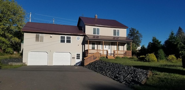 view of front of home with metal roof, driveway, a porch, and an attached garage