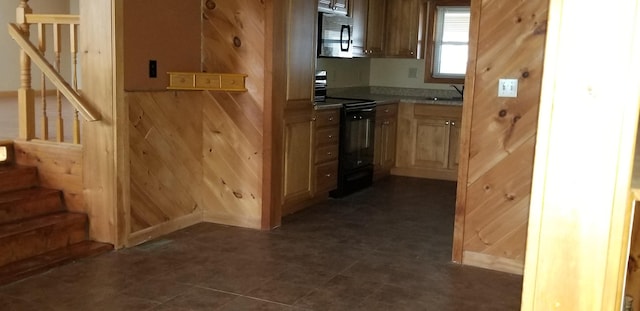 kitchen with a sink, wood walls, light countertops, and black range with electric stovetop