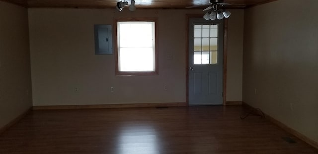 interior space with ceiling fan, electric panel, baseboards, and wood finished floors