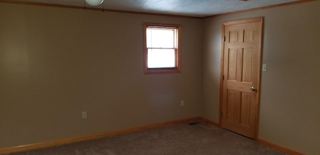 spare room with crown molding, baseboards, and carpet flooring