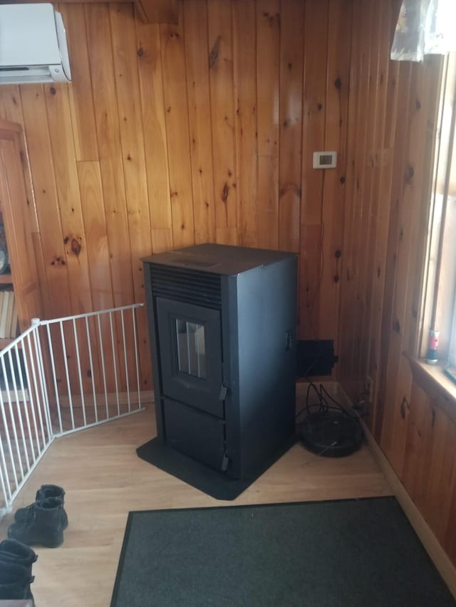 room details featuring wood walls, a wall mounted air conditioner, wood finished floors, and a wood stove