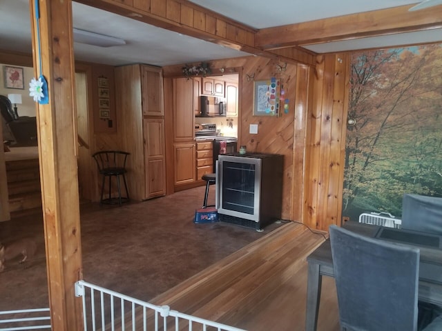 kitchen featuring black microwave, wood walls, beam ceiling, and stainless steel electric stove