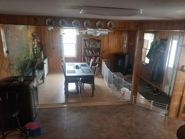 dining space with a wood stove and wood walls