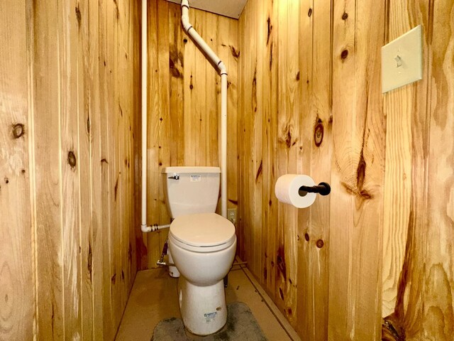 bathroom featuring toilet and wood walls