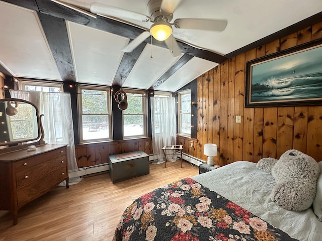 bedroom featuring lofted ceiling with beams, wood walls, a baseboard radiator, and light wood-style flooring