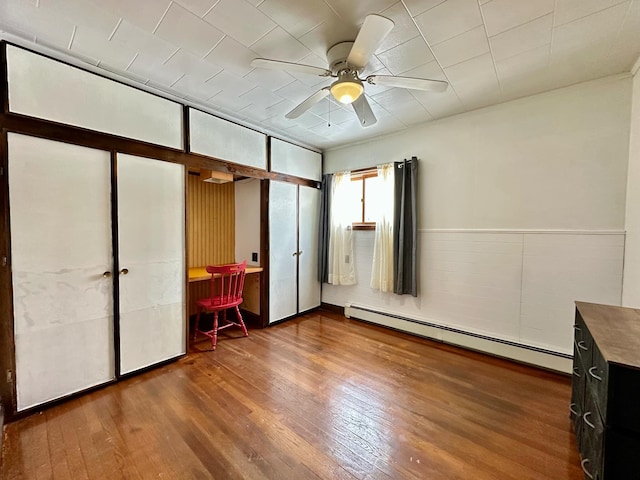 unfurnished bedroom featuring a baseboard radiator, ceiling fan, and wood finished floors