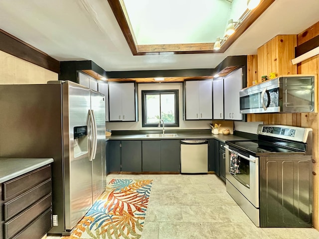 kitchen with stainless steel appliances, dark countertops, and a sink