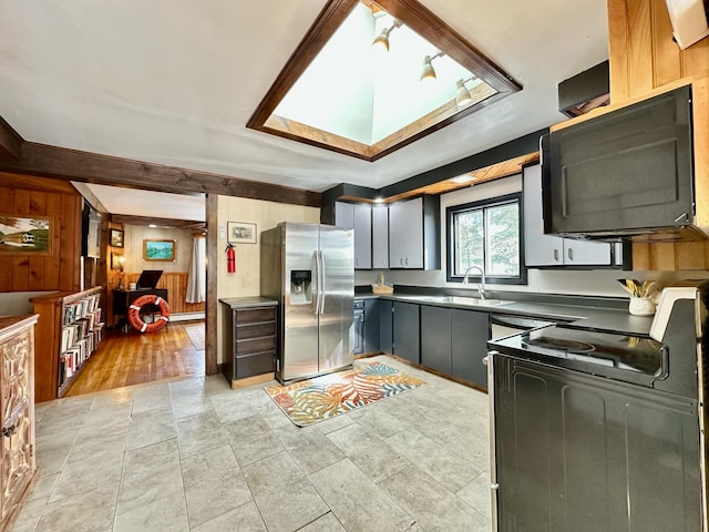 kitchen featuring a sink, wooden walls, and black appliances