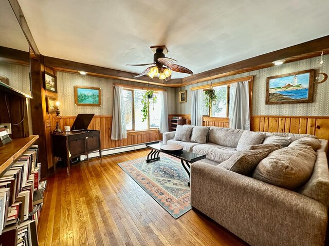 living area with a baseboard radiator, wainscoting, hardwood / wood-style floors, and wallpapered walls