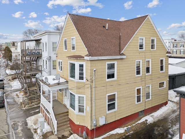 back of property with roof with shingles and stairway