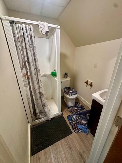 bathroom featuring a stall shower, baseboards, toilet, lofted ceiling, and wood finished floors