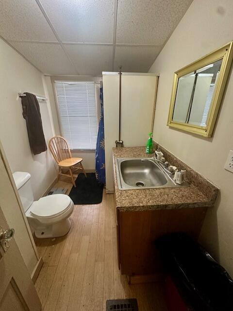 bathroom featuring visible vents, a drop ceiling, toilet, hardwood / wood-style flooring, and vanity