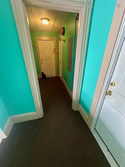 corridor with dark colored carpet and baseboards