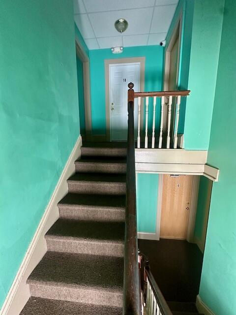 staircase featuring a drop ceiling and baseboards