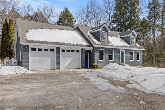 cape cod home with an attached garage and driveway