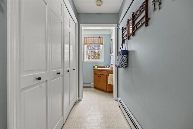 corridor with a sink, a baseboard radiator, and light floors