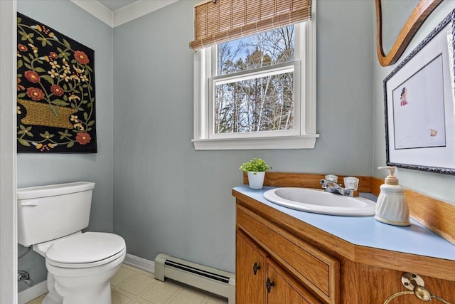 half bath featuring a baseboard heating unit, toilet, vanity, and baseboards