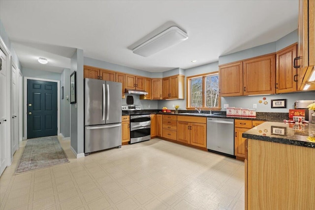 kitchen with under cabinet range hood, light floors, appliances with stainless steel finishes, and brown cabinetry