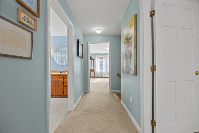 corridor featuring a sink, baseboards, and light colored carpet