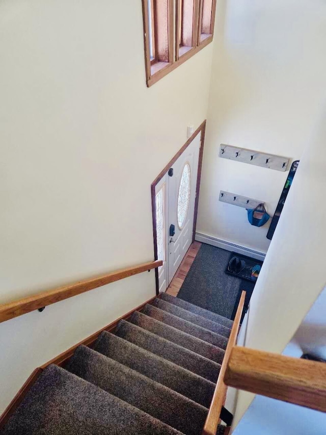 stairs featuring wood finished floors, a towering ceiling, and baseboards