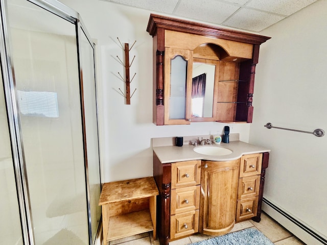 full bathroom with a baseboard heating unit, a stall shower, a paneled ceiling, and vanity