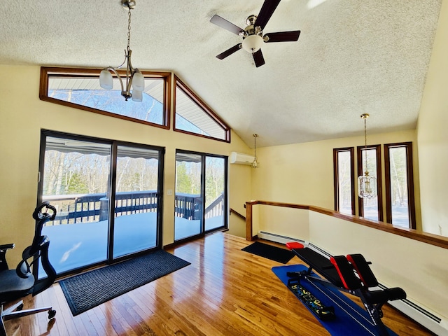 workout area featuring a chandelier, lofted ceiling, a baseboard heating unit, an AC wall unit, and hardwood / wood-style floors