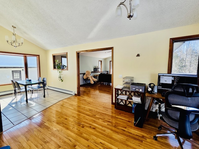 office space featuring a chandelier, lofted ceiling, a healthy amount of sunlight, and hardwood / wood-style flooring