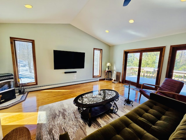 living area with lofted ceiling, a wood stove, a baseboard heating unit, and wood finished floors