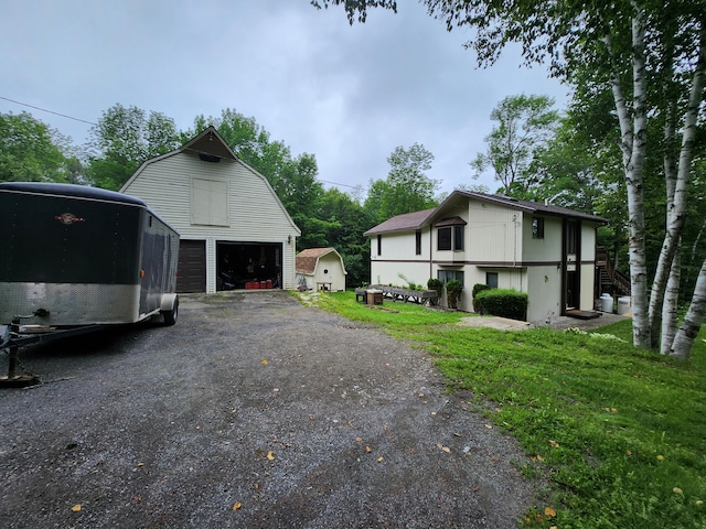 view of side of home featuring an outbuilding, a lawn, a gambrel roof, a barn, and a garage