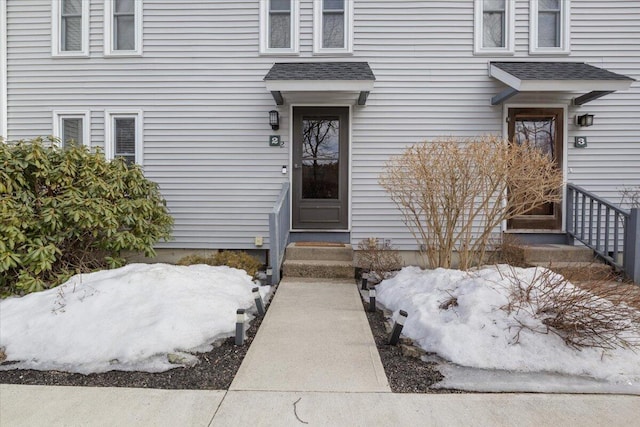 entrance to property featuring a shingled roof