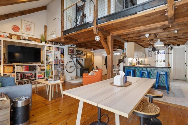 dining space featuring beam ceiling, high vaulted ceiling, and wood-type flooring