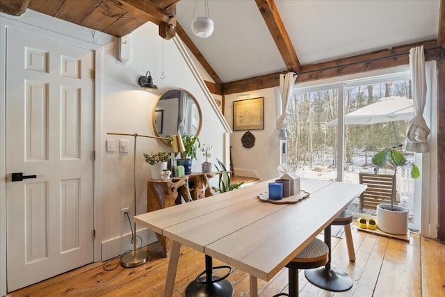 dining room with light wood-style flooring and lofted ceiling with beams