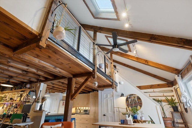 interior space featuring lofted ceiling with skylight, rail lighting, and a ceiling fan