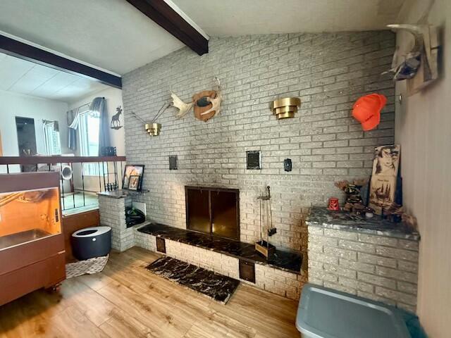 131 Clover St, Madawaska, ME 04756 - interior space with a fireplace, lofted ceiling with beams, brick wall, and wood finished floors