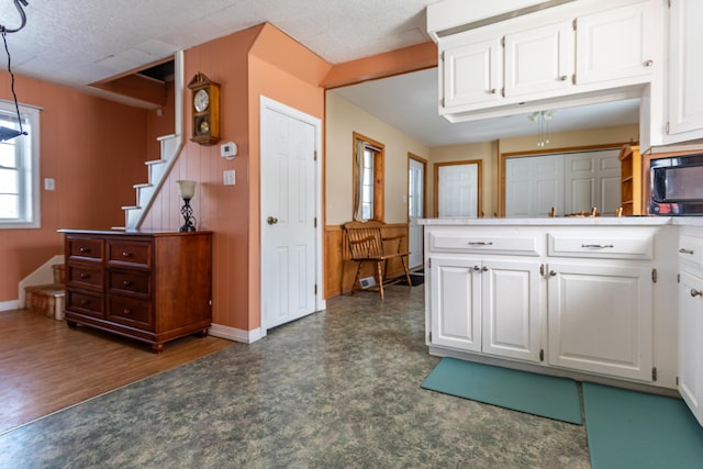 633 Main St, Madawaska, ME 04756 - kitchen with a peninsula, white cabinetry, baseboards, and decorative light fixtures
