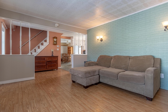 633 Main St, Madawaska, ME 04756 - living room featuring stairs, ornamental molding, brick wall, and light wood-type flooring