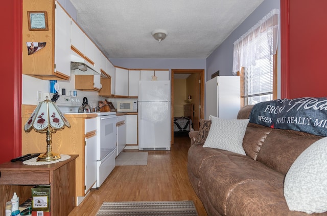 633 Main St, Madawaska, ME 04756 - kitchen with white cabinetry, white appliances, light wood-type flooring, and a textured ceiling