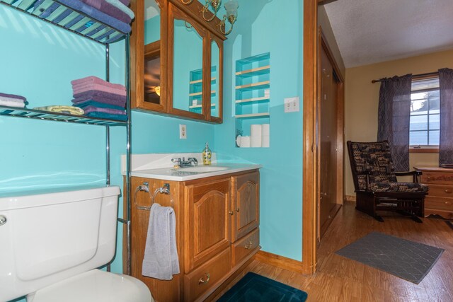 633 Main St, Madawaska, ME 04756 - bathroom featuring toilet, baseboards, wood finished floors, and vanity