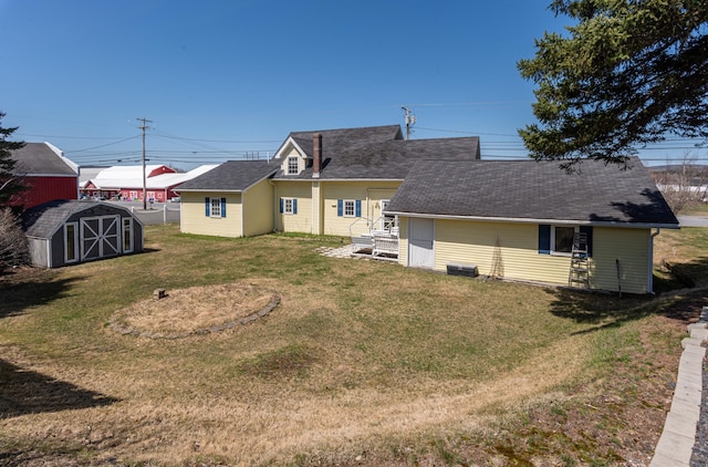 633 Main St, Madawaska, ME 04756 - rear view of house with roof with shingles, an outdoor structure, a shed, and a lawn