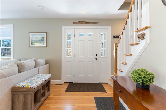 foyer featuring a wealth of natural light, stairs, and light wood-style floors