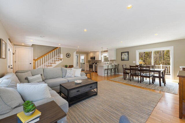 living room featuring recessed lighting, stairway, baseboards, and light wood finished floors