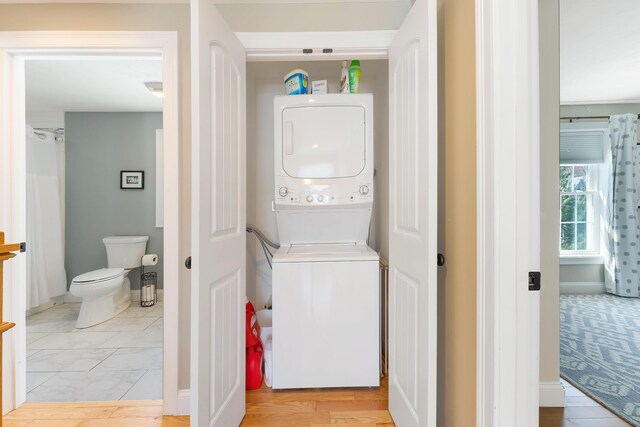 laundry area with laundry area, stacked washer and clothes dryer, and baseboards