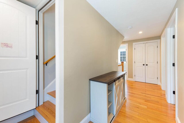 hallway featuring recessed lighting, baseboards, light wood-style flooring, and stairs